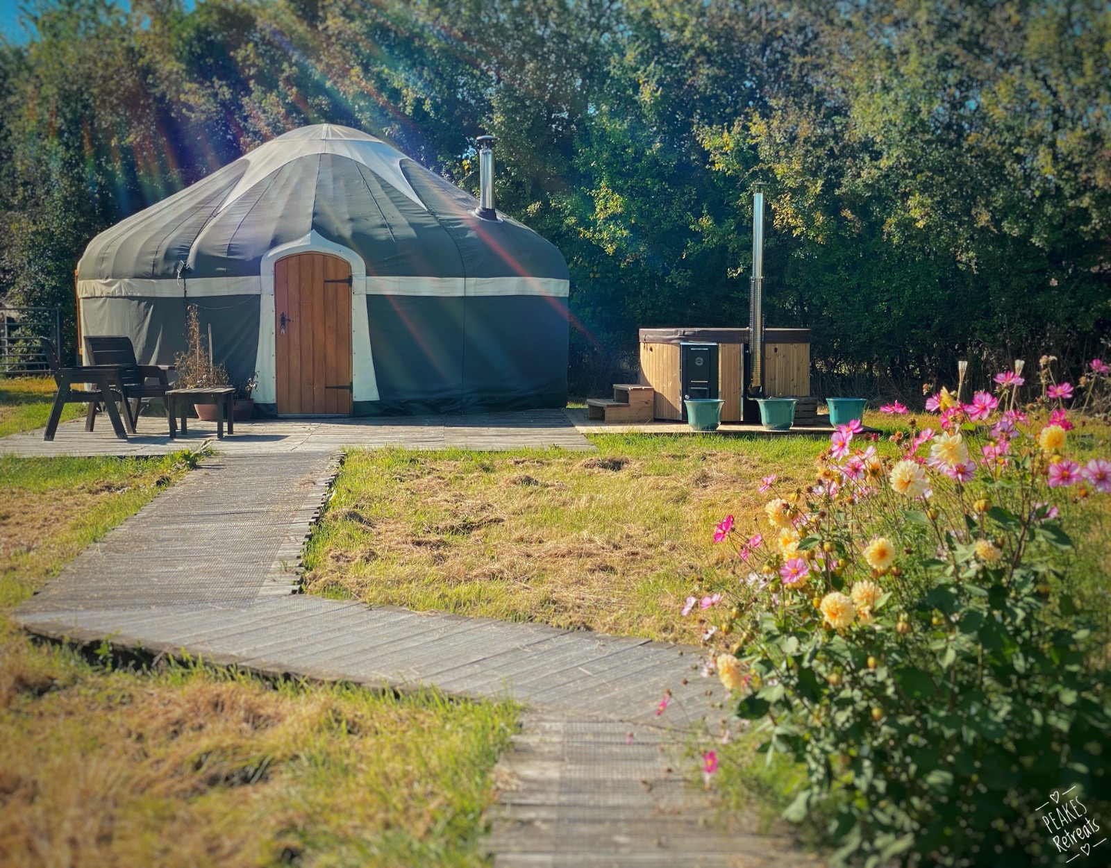Luxury glamping yurt with private wood fired hot tub surrounded by pretty flowers and nature